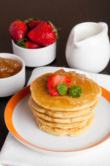Delicious pancakes with fresh strawberries on a plate, jam and m