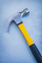 Yellow claw hammer with rubber handle on metallic background con
