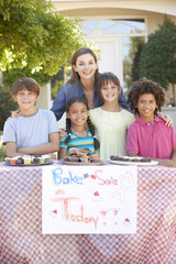 Group Of Children Holding Bake Sale With Mother
