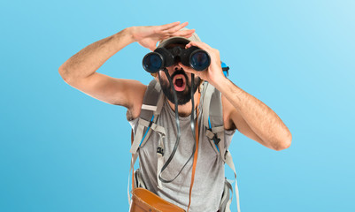 Backpacker with binoculars over isolated white background