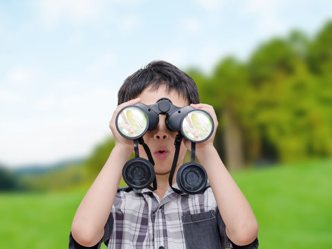 Young Asian boy using binoculars in forest