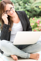 Junge Frau arbeitet draussen am Laptop