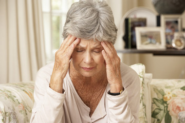 Unhappy Retired Senior Woman Sitting On Sofa At Home