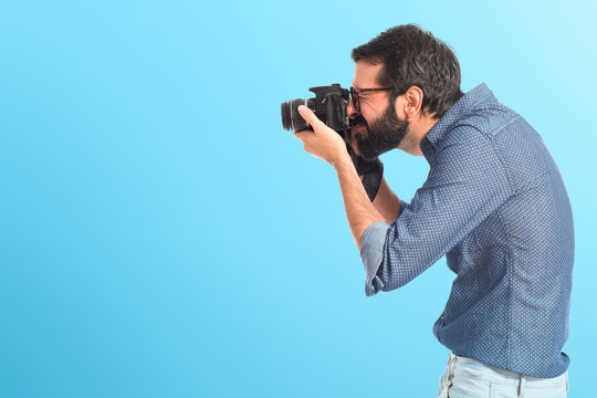 Young hipster man photographing over white background