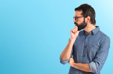 Young hipster man thinking over white background