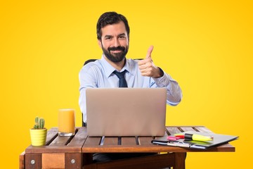 Businessman in his office with thumb up