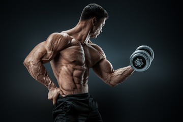 Power athletic man bodybuilder doing exercises with dumbbell