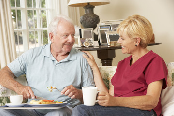 Helper Serving Senior Man With Meal In Care Home
