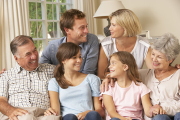 Multi Generation Family Group Sitting On Sofa Indoors