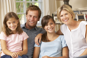 Family Group Sitting On Sofa Indoors