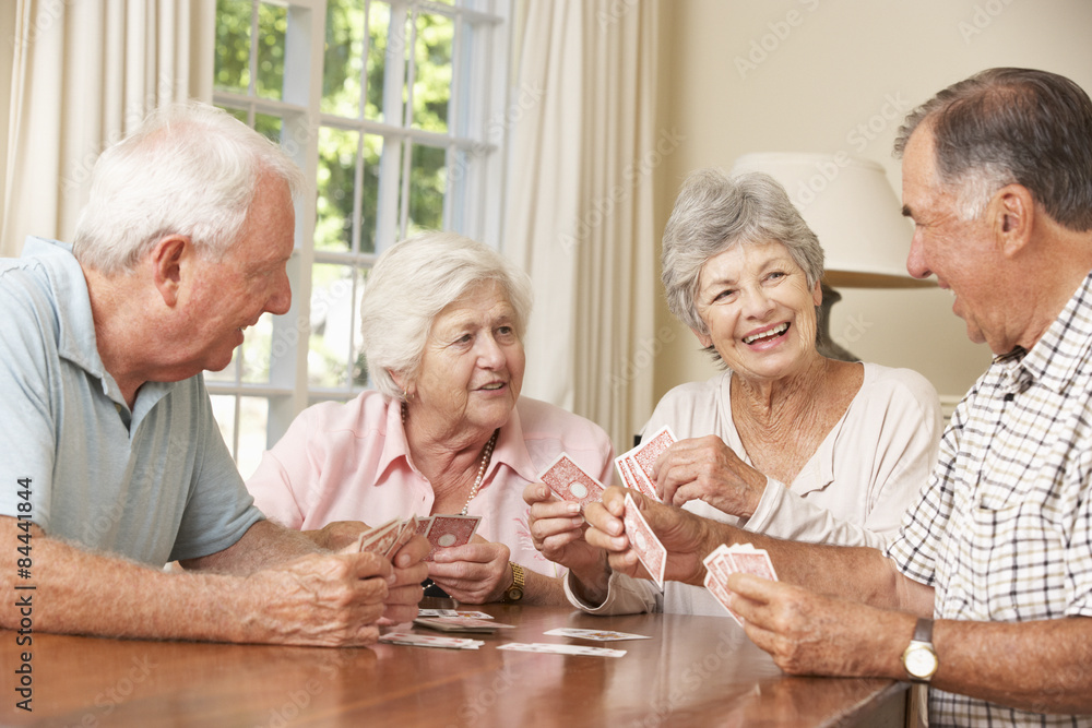 Wall mural group of senior couples enjoying game of cards at home