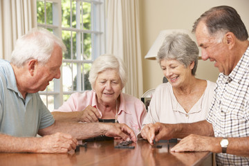 Group Of Senior Couples Enjoying Game Of Dominoes At Home