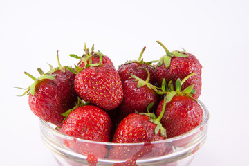Transparent glass bowl with strawberries on white