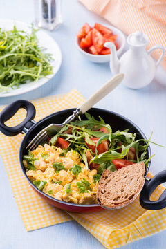 Scrambled eggs with fresh salad in frying pan