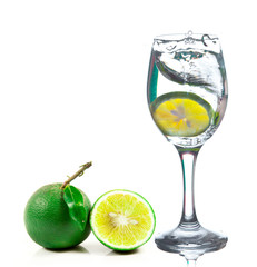 Lime splashing into glass of water on white background