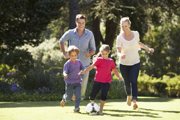 Obraz premium Family Playing Football In Garden Together