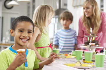 Group Of Children Enjoying Birthday Party Food At Table