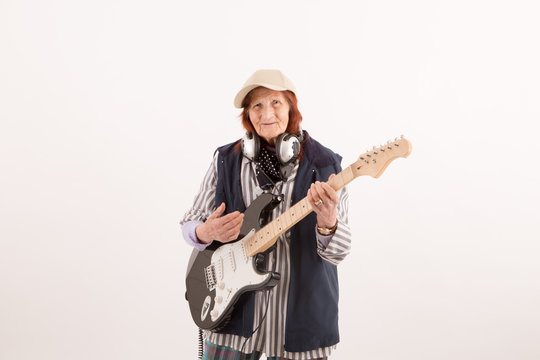 Funny elderly lady playing electric guitar.