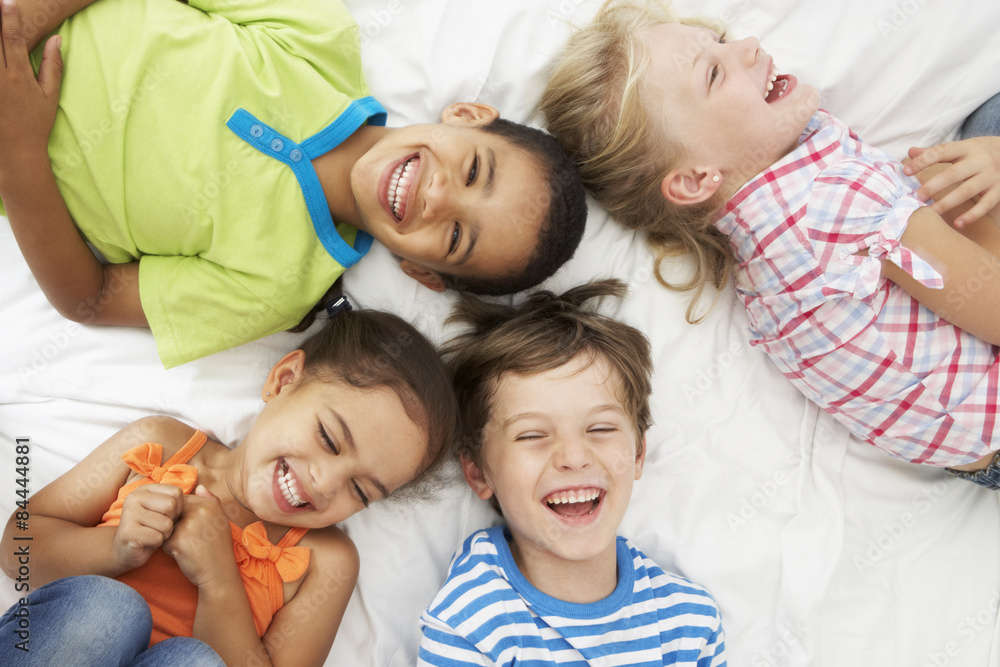 Wall mural Overhead View Of Four Children Playing On Bed Together