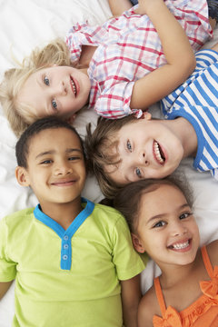 Overhead View Of Four Children Playing On Bed Together