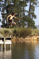 Fototapeta na wymiar Boy Jumping From Jetty Into Lake
