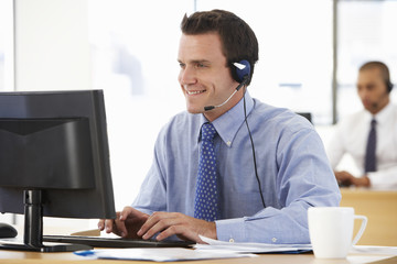 Friendly Service Agent Talking To Customer In Call Centre