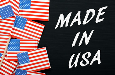 Fototapeta na wymiar The phrase Made In USA with flags on a blackboard