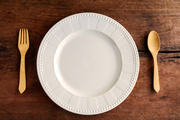 Empty dish with wooden spoon and fork on old wood