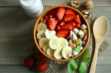 The breakfast of oatmeal, strawberries and milk on wooden background