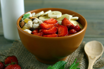 The breakfast of oatmeal, strawberries and milk on wooden background