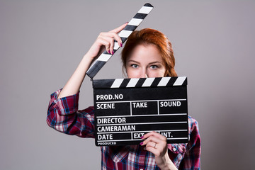 Beautiful red-haired woman holding a movie clapper, isolated ove