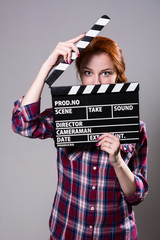 Beautiful red-haired woman holding a movie clapper, isolated ove