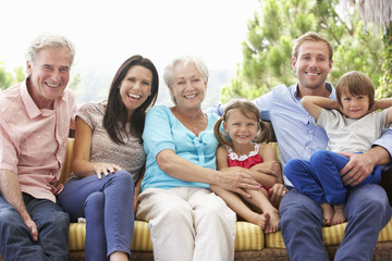 Multi Generation Family Sitting On Garden Seat