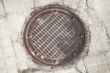 Round rusted hatch in urban pavement