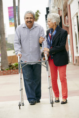Wife Helping Senior Husband To Use Walking Frame