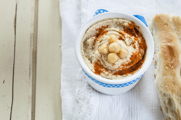 Hummus im Schälchen, weißer Holzgrund, Fladenbrot, Textfreiraum