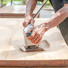 Hand of worker sanding the old wood table.