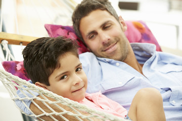 Father And Son Relaxing In Garden Hammock Together