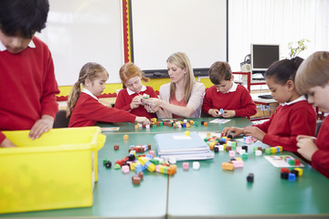Pupils And Teacher Working With Coloured Blocks