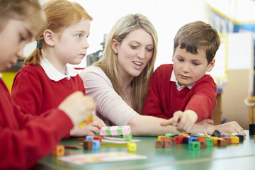 Pupils And Teacher Working With Coloured Blocks