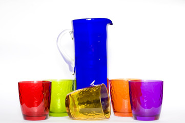 Blue glass carafe and glass colored glasses on a white background