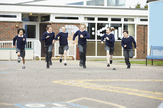 Group Of Elementary School Pupils Running In Playground