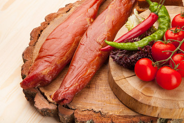Smoked meat with bright summer vegetables on wooden background