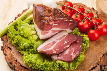 Smoked meat with bright summer vegetables on wooden background