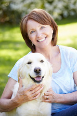 Portrait Of Mature Woman Sitting In Field With Dog