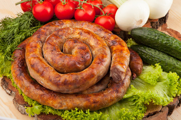 Smoked meat sausage salami with bright summer vegetables and bread on wooden background