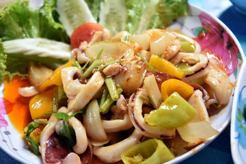 Fried squid in yellow curry powder on dish holding by hand of ma