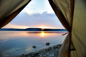 Sunset from the green tent on lake coastline