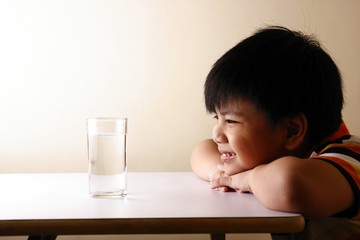 Kid looking at a glass of water on a wooden table