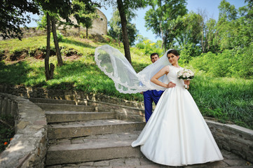 Young wedding couple in love on their wedding day, veil on wind